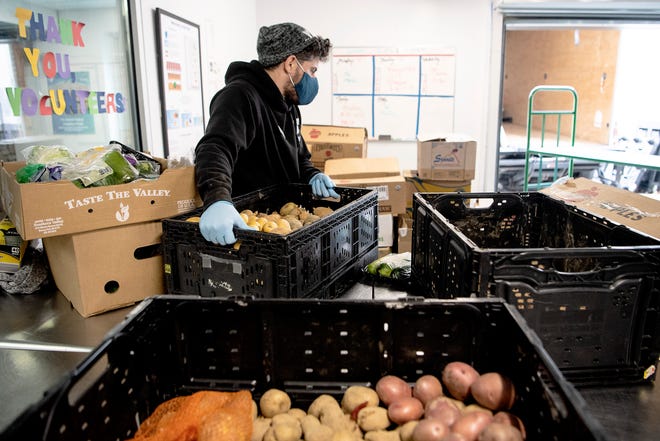 Miguel Hernandez, operations manager for YMCA's mobile market, sorts through donated produce in Asheville January 25, 2022.
