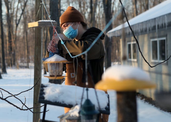 Thatcher Dietz, a Westerville South High School junior, fills bird feeders with seed to attract them for identification and to study migration patterns as part of a wildlife-resource-management class through the Delaware Area Career Center on Jan. 26 at Camp Lazarus in Delaware.