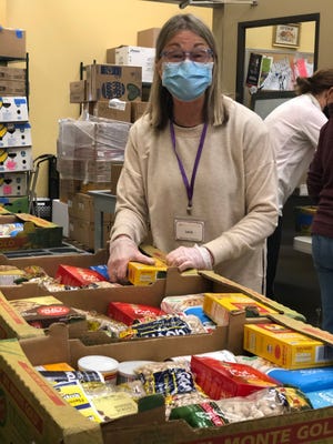 An Open Table volunteer packs boxes with foods culturally appropriate for Afghan refugees, such as spices, rice and loose tea as well as baking supplies.