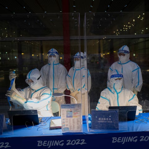 Olympic workers in protective gear work at a crede