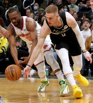 New York Knicks guard Kemba Walker (8) and Milwaukee Bucks guard Donte DiVincenzo (0) vie for a loose ball  during the second half of their game Friday, January 28, 2022 at Fiserv Forum in Milwaukee, Wis. The Milwaukee Bucks beat the New York Knicks 123-108.