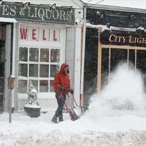 Shopkeepers clear snow from their sidewalks on Yon