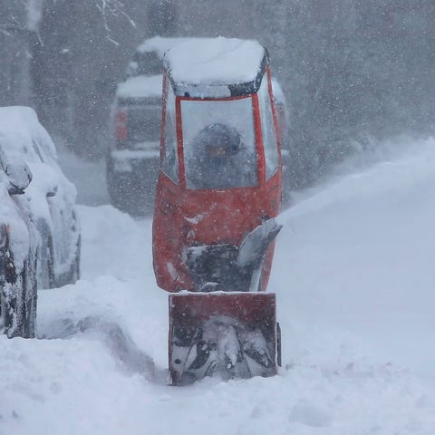 Mark Magrath uses a snowblower to clear his neighb