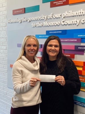 Kristin Irwin, CEO of the Monroe Family YMCA (left), accepts a donation from Nicole Thorpe, Key Bank vice president and senior business banking relationship manager.