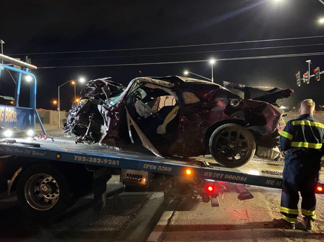A crumpled maroon Dodge Challenger is towed away after an hourslong crash investigation in North Las Vegas on Saturday, Jan. 29, 2022. Nine people were killed, including seven family members, after the Dodge blew through a red light at more than 100 mph, authorities said.
