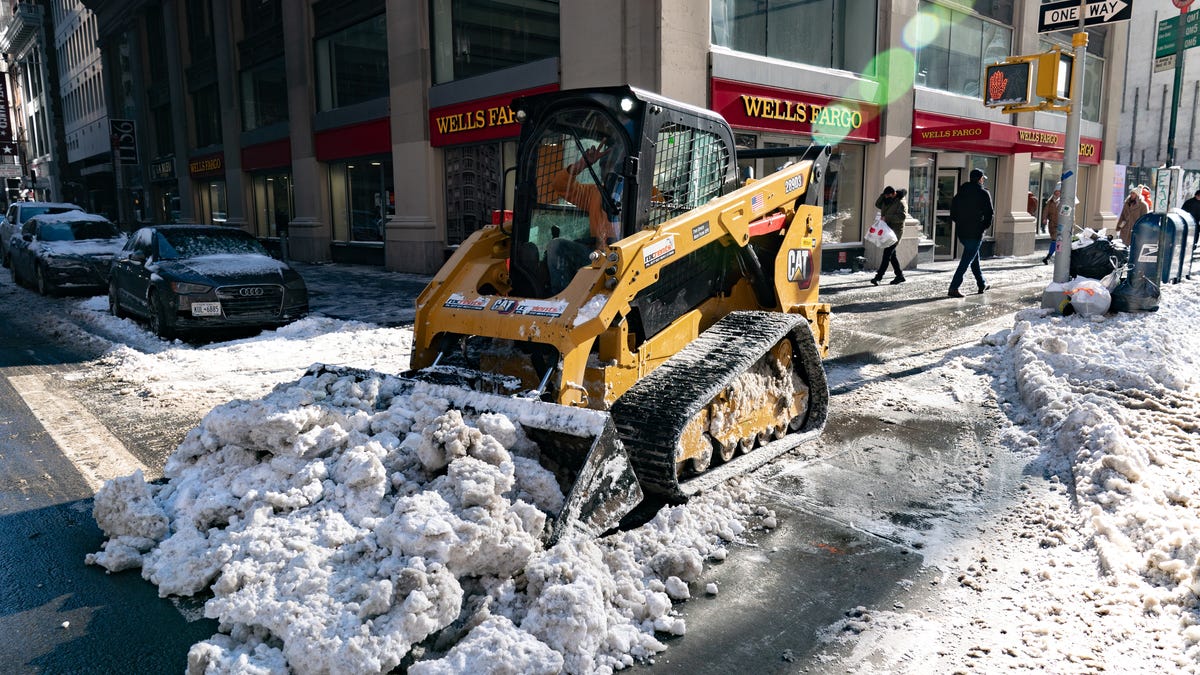 Workers plow snow on 6th Avenue after a blizzard hit the Northeast on January 30, 2022 in New York City. A powerful nor'easter brought blinding blizzard conditions with high winds causing some power outages to the Mid-Atlantic.