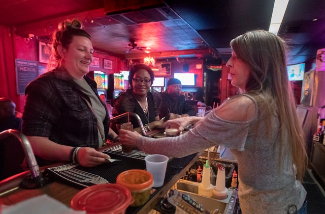 Bartender Tina Bailey (right) hands a drink to Francis Pierce at the Azalea Cocktail Lounge in Pensacola on Monday, January 31, 2022.