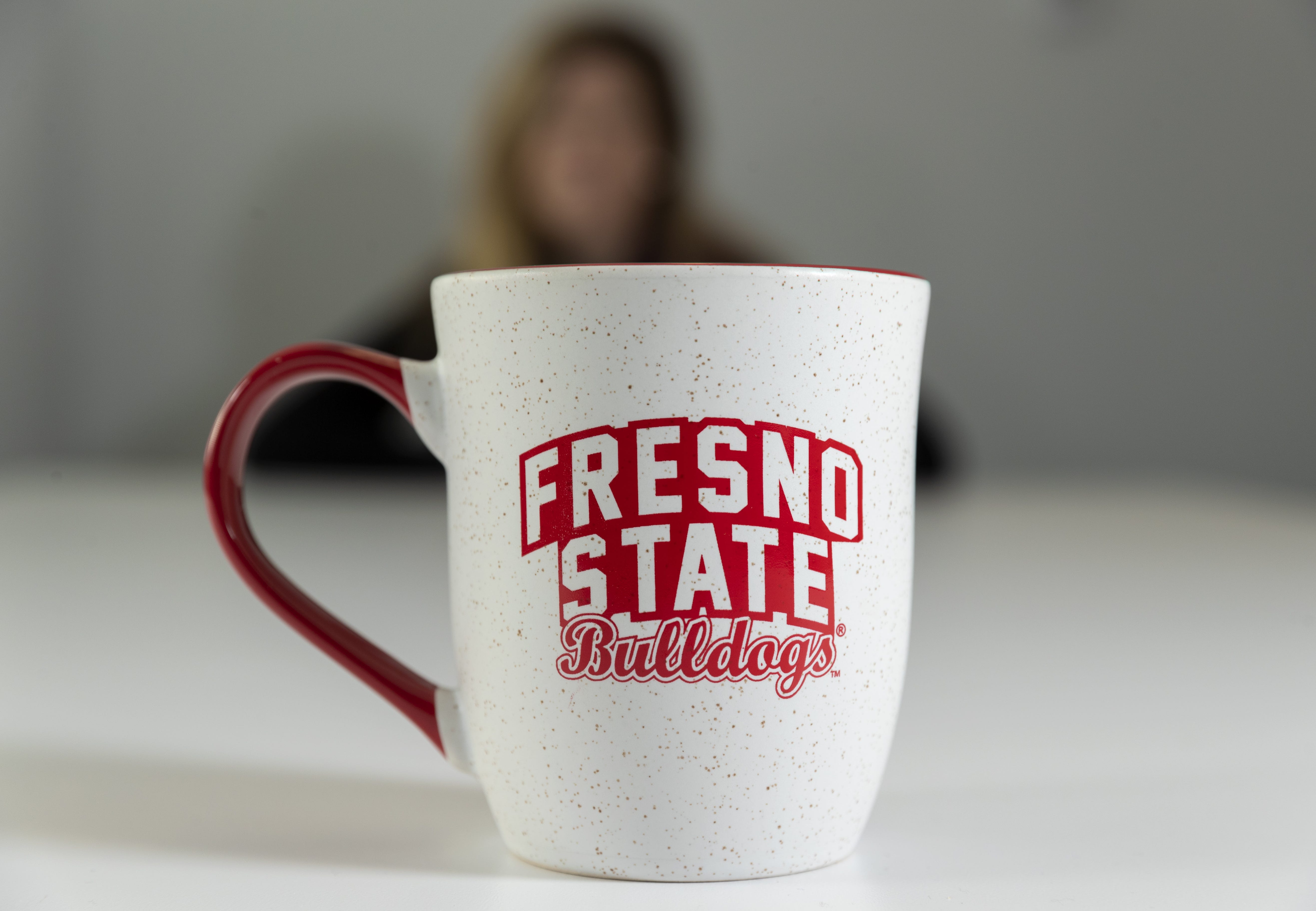 A former doctoral student who worked full-time for Frank Lamas sits, out of focus, behind a Fresno State coffee mug. She filed a Title IX complaint against him in October 2019 saying he sexually harassed her for nearly a year.