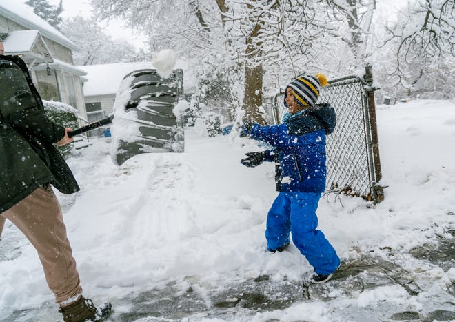 Zander Heyza, of Flint, throws snow at his mother, Negan Heyza, as she shovels outside of their home on Thomson Street in Flint on Feb. 2, 2022, after his school was canceled following an early morning snowstorm that blanketed the area.
