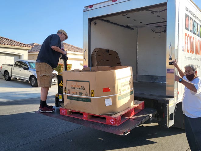 Two volunteers from Food Now load on to a truck a large container of fruit donated by Sun City Palm Desert in January 2022.