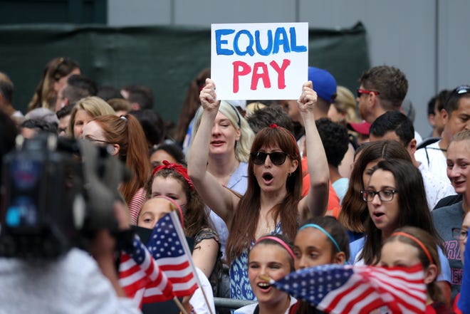 Fans along the parade route chant for equal pay as they wait for the United States women's national soccer team in July 2019