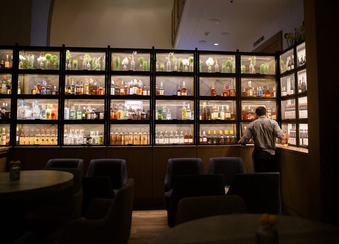 Bartender Robert Dalphonse grabs a fresh bottle from the on-display liquor cabinet at the Corinne Restaurant, located on the first floor of the Austin Downtown Marriott Hotel. Although the Texas economy continues to recover amid the COVID pandemic, a new survey shows the service sector remains challenging. Statesman file photo