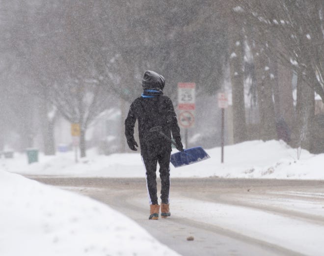 A man walks on north Freedom street in Ravenna with a snow shovel. Sidewalks had yet to be cleared.