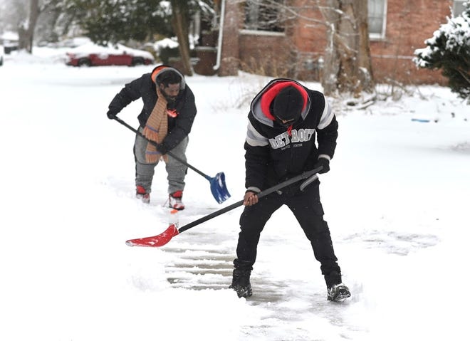 Gregory McGhee, left, and Carlos Pennington shovel snow around their neighborhood, making a point to clear the homes of senior citizens on Lantz Street at Charest in Detroit on Thursday, February 3, 2022.