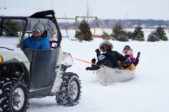 Chris Jury, of Hilliard, pulls his wife and kids and members of a friend's family in a canoe around their property Friday. They started this snow canoe tradition last year, saying, 