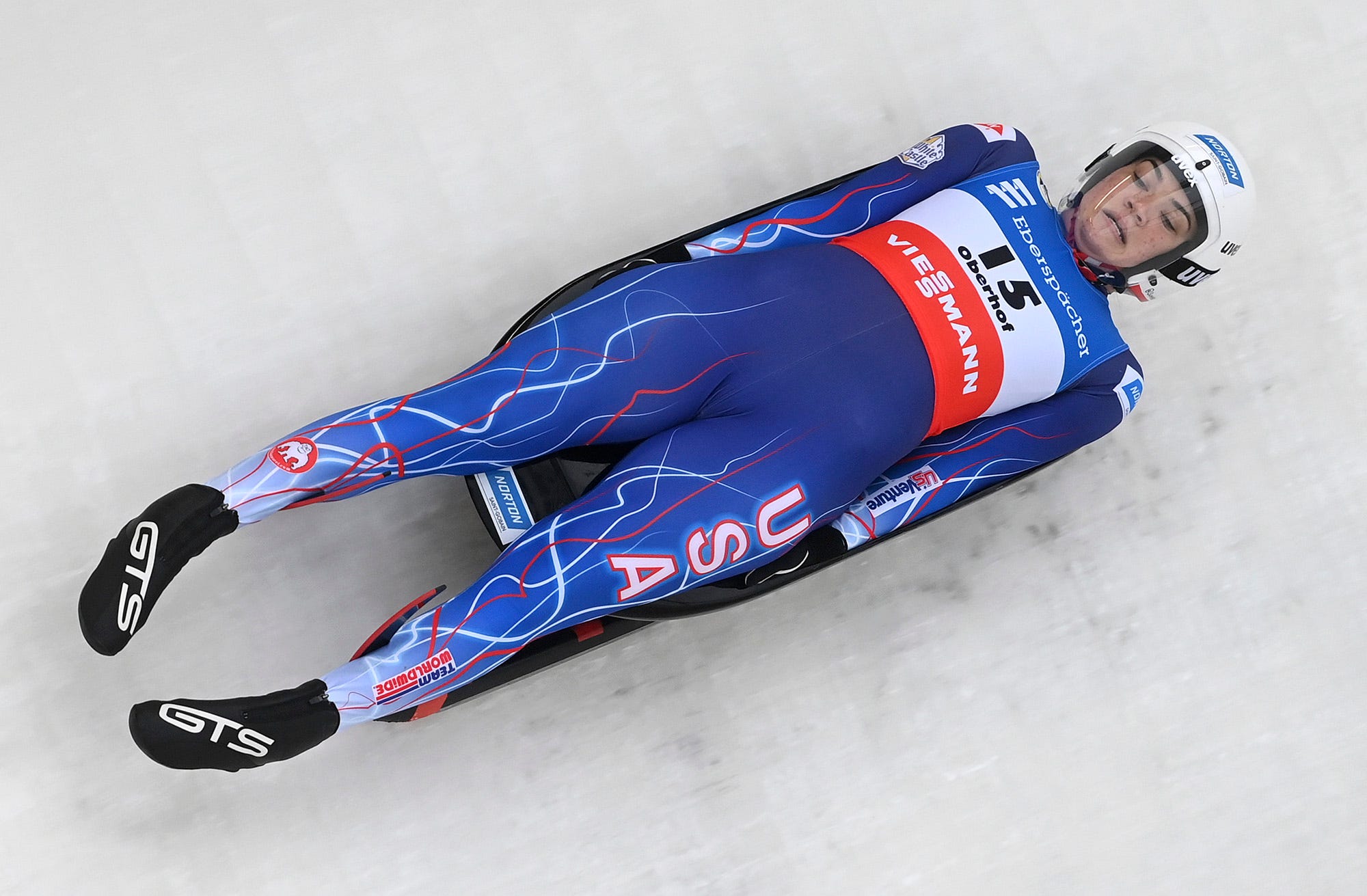 Summer Britcher from USA Luge steers a sled, wears a helmet and dons a racing uniform that all have Norton Saint-Gobain logos on them during the World Cup last month in Switzerland. Britcher and USA Luge, currently in China for the 2022 Winter Games, are sponsored by the Worcester-based company Norton Saint-Gobain.