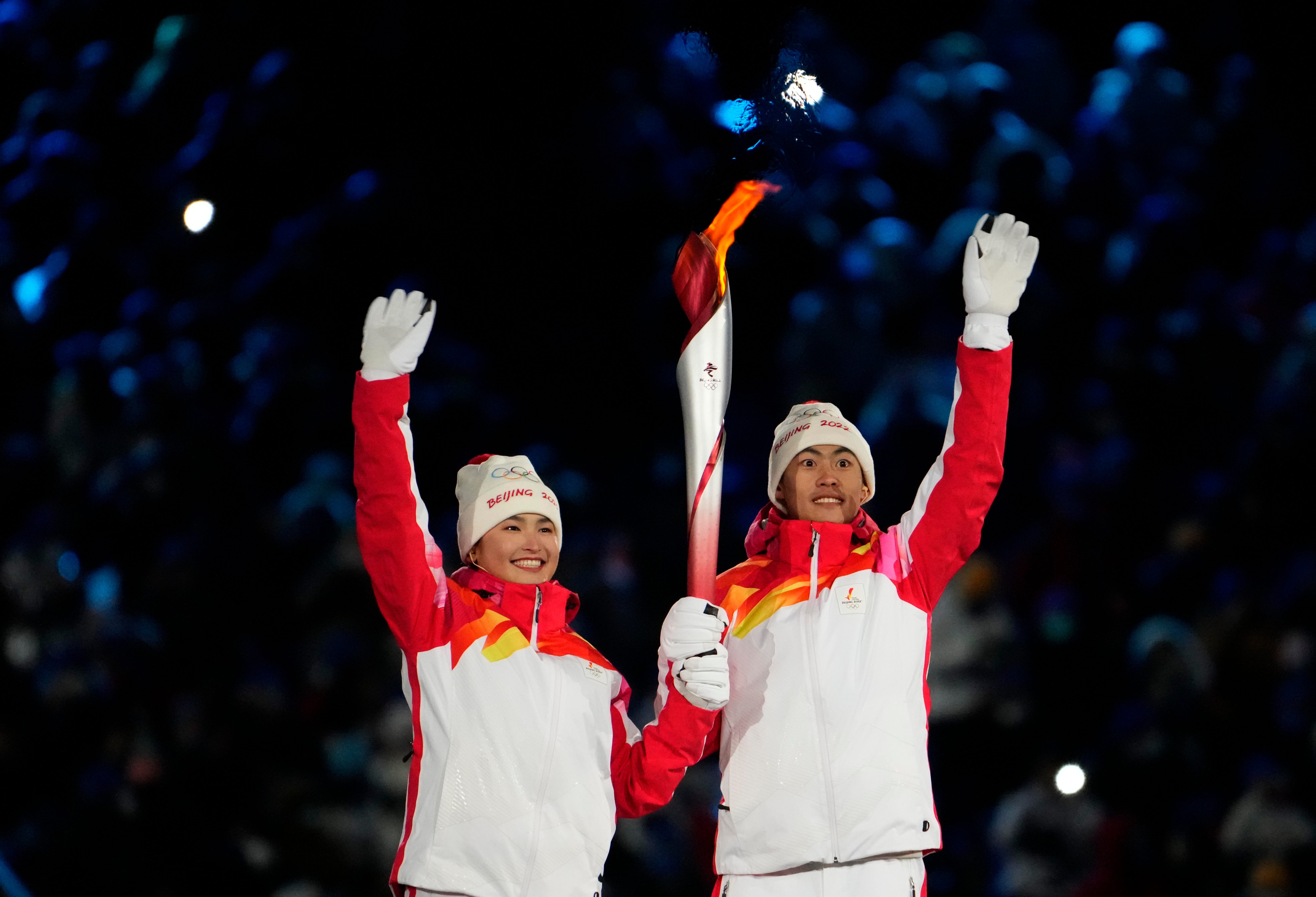 Torch bearers Zhao Jiawen and Dinigeer Yilamujiang wave during the Opening Ceremony of the Beijing 2022 Winter Olympic Games at Beijing National Stadium.