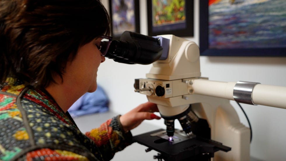 Dr. Elizabeth Bundock uses a microscope to help investigate causes of death as the Vermont chief medical examiner