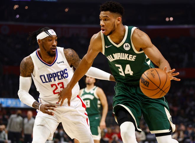Giannis Antetokounmpo #34 of the Milwaukee Bucks dribbles the ball against Robert Covington #23 of the LA Clippers in the second quarter.