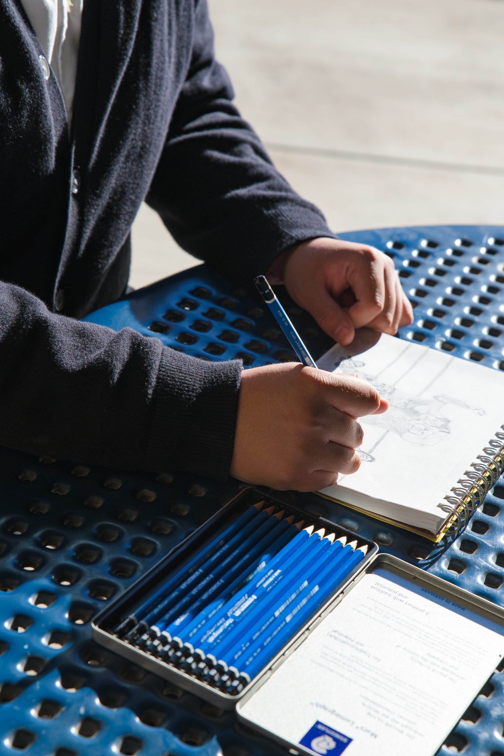 Cesar Soberanes, a 19-year-old Art Education major and recipient of the Helios Adelante Scholarship, sketches for a picture outside the Arts Building at Phoenix College.