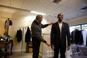 Former Broadway star Russell Joel Brown (right) gets fitted for a suit by International Formal Wear owner Henry Ingram in the store on a recent Friday. Brown is reviving his show Mozart to Motown to benefit his nonprofit, Boys with a Future.