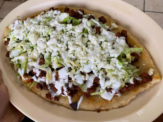 A huarache is a corn based masa snack, topped with al pastor meat and crema at Panaderia Cristal.