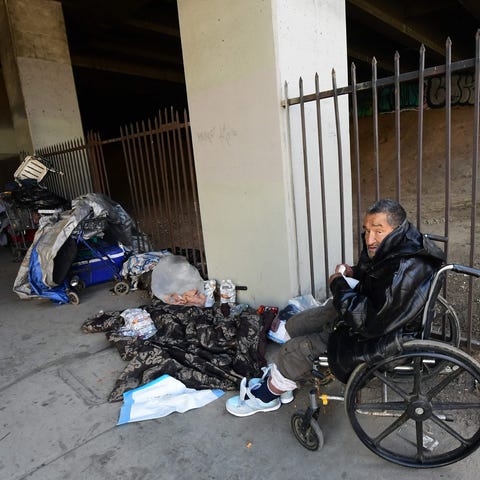 A homeless man sits in his wheelchair beside a sig