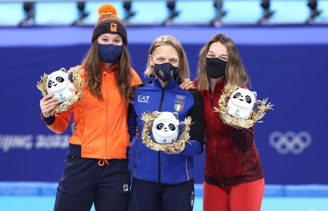Short-track speedskating gold medalist Arianna Fontana of Team Italy (center), silver medalist Suzanne Schulting of the Netherlands (left) and bronze medalist Kim Boutin of Canada (right) pose with Bing Dwen Dwen mascots during the women's 500 meter flower ceremony.