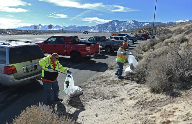 NDOT employees Robert Iverson, left, and Sandy Martensen pick up debris at the Park & Ride lot on HWY 50 and HWY 395 in Carson City on Feb. 9, 2022.