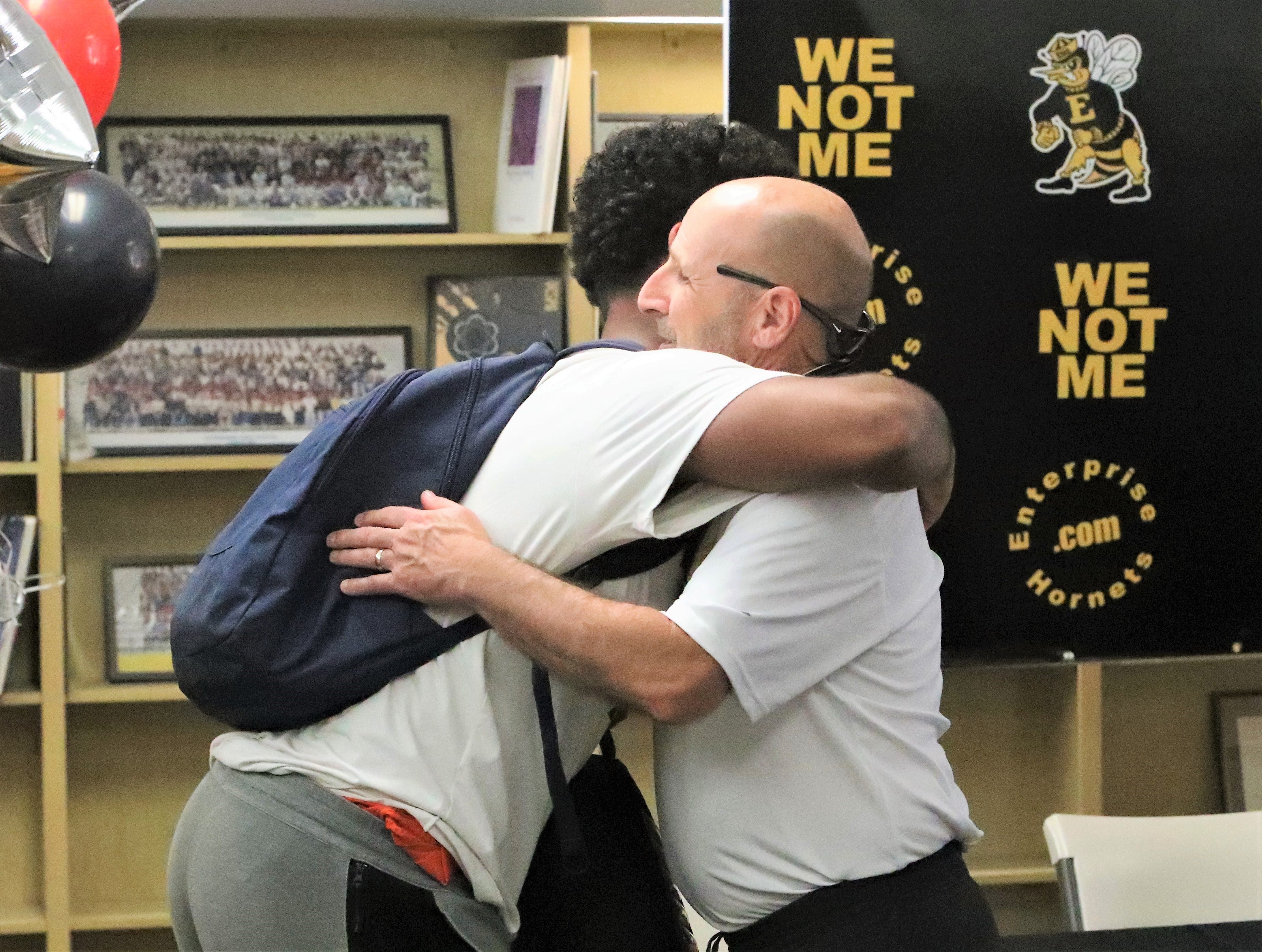 Peoples receives a hug from coach Jim Deaver after Peoples signed a letter of intent to play football at Southern Oregon University.