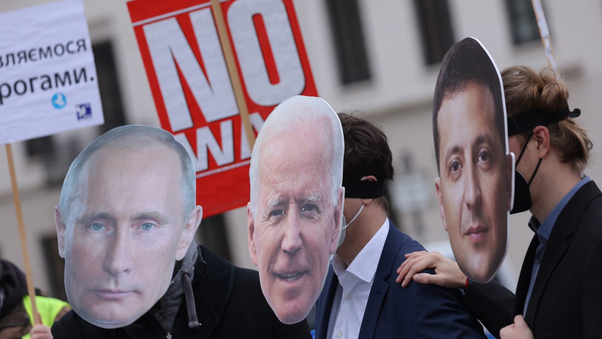 Protesters dressed as Russian President Vladimir Putin, left, U.S. President Joe Biden and Ukrainian President Volodymyr Zelenskyy, right, attend a small rally to demand a diplomatic solution to the current threat of war in Ukraine on Feb. 9, 2022, in Berlin. Russia has amassed thousands of troops along its border to Ukraine, causing international fears of a possibly imminent military invasion.