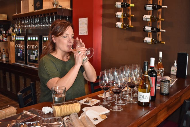 Beth DeVries, owner of Della Viti wine bar on Ames' Main Street, tastes a wine to pair with a Girl Scout cookie.