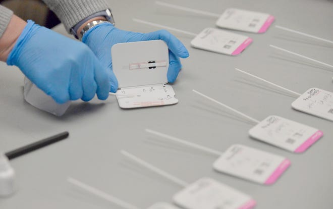 A school nurse processes a swab from a student who took a rapid COVID-19 test.