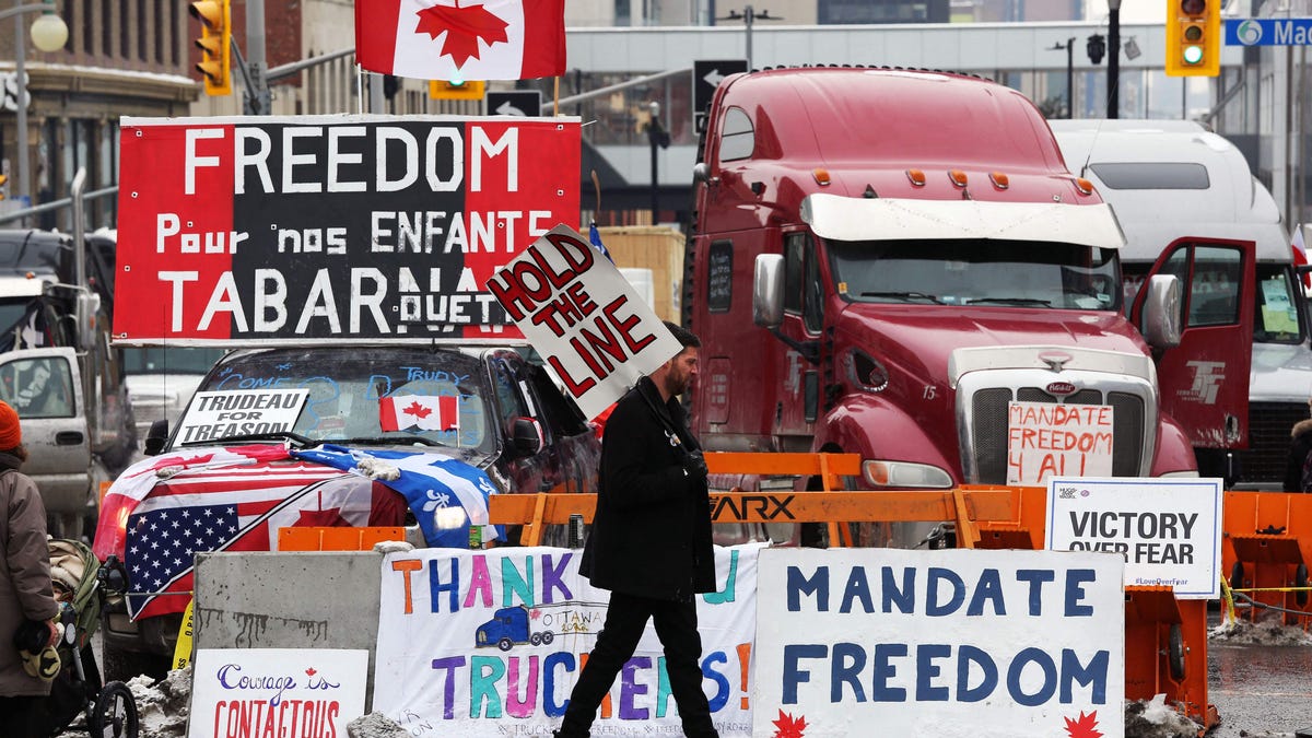 A protester walks in front of parked trucks as demonstrators continue to protest the vaccine mandates implemented by Prime Minister Justin Trudeau on February 8, 2022 in Ottawa, Canada.