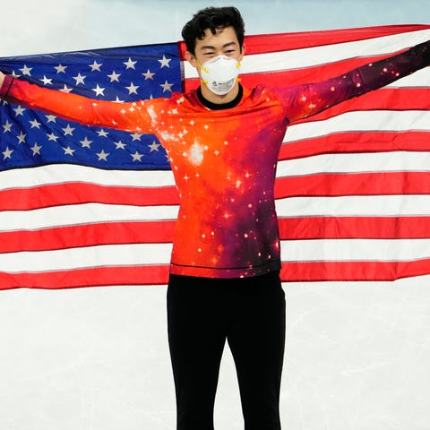 A proud Nathan Chen holds the American flag behind