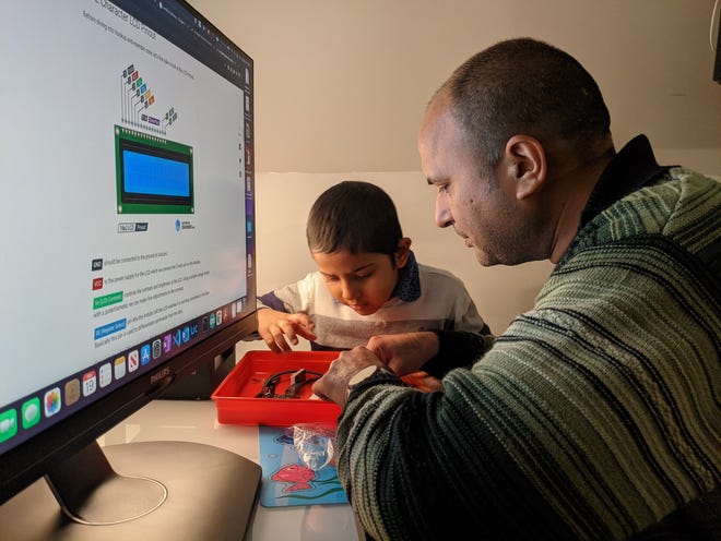 Amit Kumar and his son, Ray, work on a do-it-yourself electronics project. Ray, who has autism, responded quickly to the standard treatment, but the family's health plan in Virginia, Anthem Blue Cross and Blue Shield, said it was not included or not medically necessary. The family moved to Irvine, Calif. over Christmas 2021 solely because California more strictly regulates coverage.