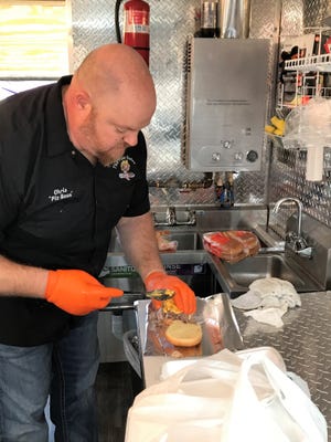 Chris Goergen loads up a Mac Daddy sandwich with pulled pork and macaroni and cheese inside the Fine Swine food truck on Sunday, Feb. 13, 2022.