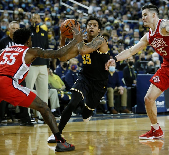 Michigan guard Eli Brooks (55) drives to the basket against Ohio State guard Jamari Wheeler (55) and forward Kyle Young (25) on Saturday in Ann Arbor, Michigan. Brooks scored 17 points in the game to pass the 1,000-point milestone for his career.