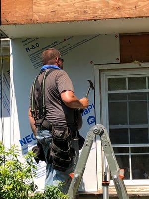A contractor installs rigid insulation on a home during an NJIT project looking at reducing heat loss and saving energy.