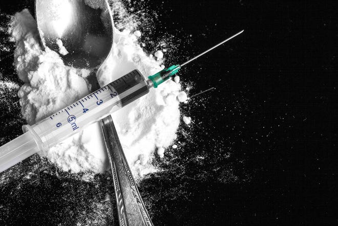 Drug syringe and heroin on spoon