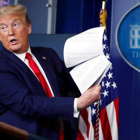 President Donald Trump holds up documents as he sp