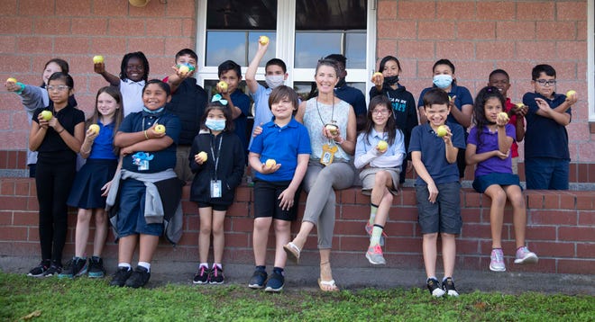 Third grade teacher, Heather Stallings, smiles with her students after receiving the Golden Apple award from Champions For Learning on Thursday, Feb.  17, 2022 at Calusa Park Elementary in Naples, Fla.  The education foundation made a surprise visit to six schools to recognize teachers and their classroom best practices.