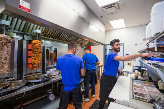 Ali el-Zubaidi, solda, Muhammed el-Jubouri, ortada ve Youssef al-Zubaidi, 17 Şubat 2022'de Chandler'daki Supreme Shawarma'nın mutfağında yemek hazırlıyor.