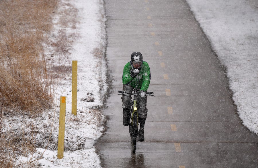 A lone cyclist moves along the path along Cherry Creek in Denver, Colorado. as a winter storm sweeps over the intermountain West on Wednesday, Feb. 16, 2022.