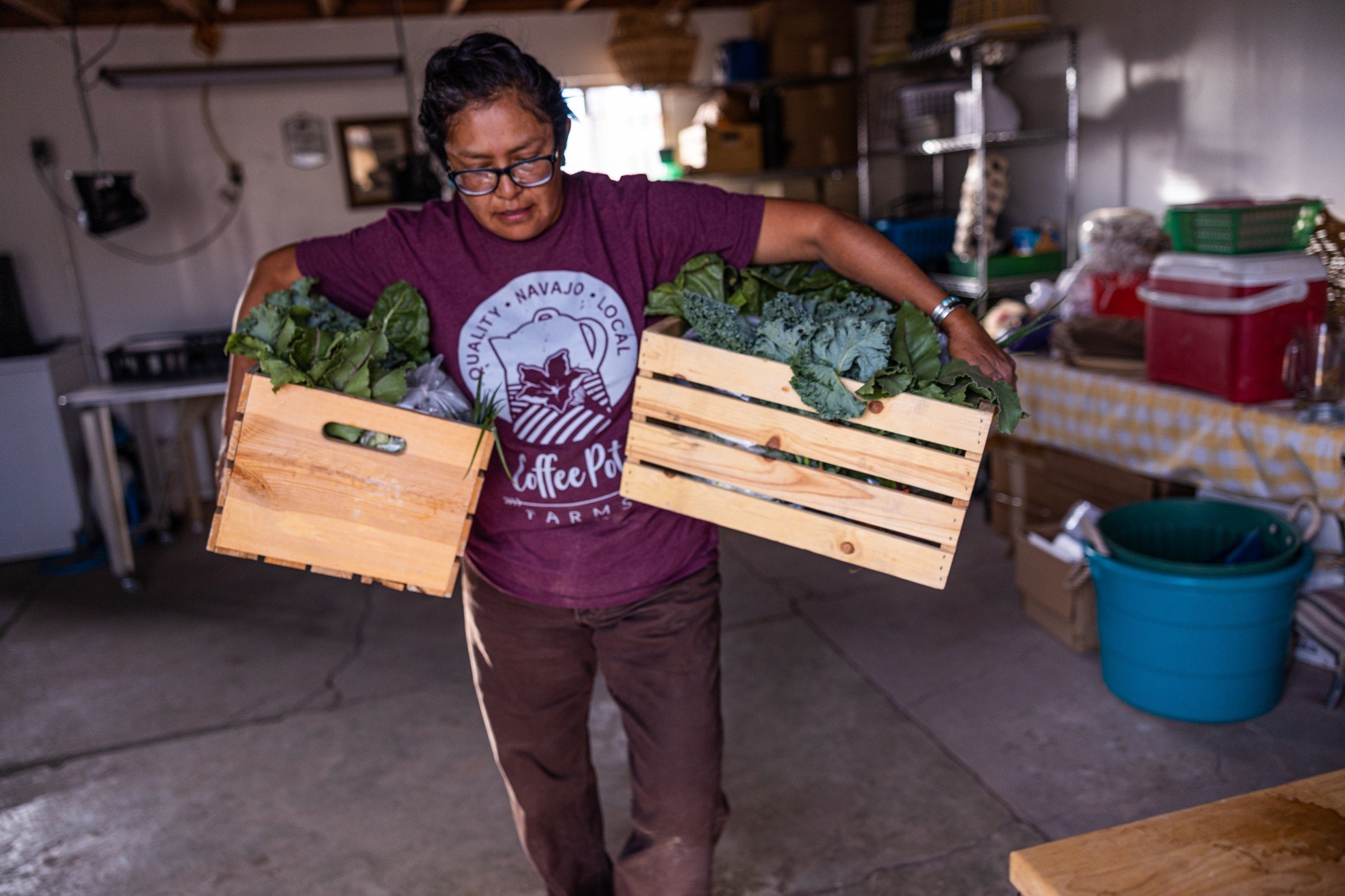 Cherilyn Yazzie carries vegetable boxes she grew at her farm in Dilkon, Arizona.