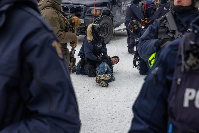 Police detain a demonstrator participating in a protest organized by truck drivers opposing vaccine mandates on Feb. 19, 2022, in Ottawa, Ontario. The drivers have used vehicles to form a blockade that has blocked several streets near Parliament Hill.  Prime Minister Justin Trudeau has invoked the Emergencies Act in an attempt to try to put an end to the demonstration that has nearly paralyzed a portion of downtown Ottawa for three weeks.