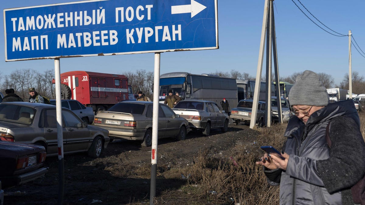 A woman looks at her mobile phone near a queue of cars as they cross the Russian border check point near the town of Uspenka, on Feb. 19, 2022.