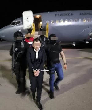 Jose Bryan Salgueiro Zepeda, who is accused of being a leader in "Los Salgueiro" crime family, is escorted off a Mexican air force plane after landing in Chihuahua City following his arrest Friday during a baptism in a church in Culiacan, Sinaloa.