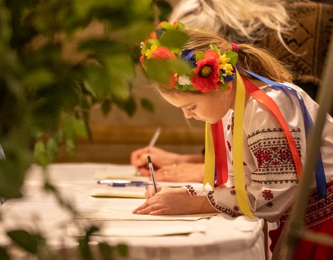 Attendee Ksenia Zagaiko, 8, signs a letter calling for action to be sent to President Joe Biden during the "Stand with Ukraine" rally at the Ukrainian Cultural Center in Warren on Sunday, Feb. 20, 2022. Citizens gathered to discuss their feelings on the tensions between Ukraine and Russia.