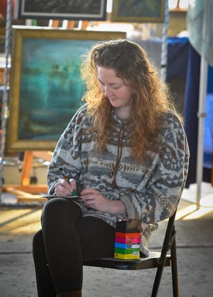 Shelby Bork, a permanent artist at The Arts Garage, paints a matchbook cover for a Minnesota phillumenist.